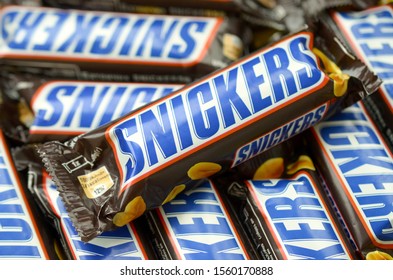 Many Snickers Chocolate Bars Stacked Close Up. Snickers Bars Are Produced By Mars Incorporated. Snickers Was Created By Franklin Clarence Mars In 1930