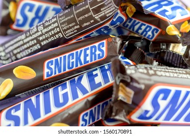 Many Snickers Chocolate Bars Stacked Close Up. Snickers Bars Are Produced By Mars Incorporated. Snickers Was Created By Franklin Clarence Mars In 1930