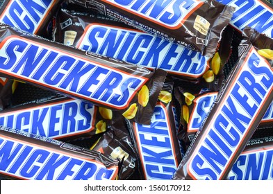 Many Snickers Chocolate Bars Stacked Close Up. Snickers Bars Are Produced By Mars Incorporated. Snickers Was Created By Franklin Clarence Mars In 1930