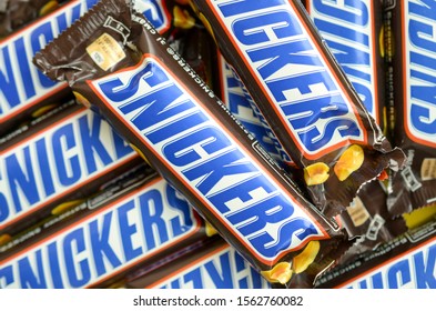 Many Snickers Chocolate Bars Stacked Close Up. Snickers Bars Are Produced By Mars Incorporated. Snickers Was Created By Franklin Clarence Mars In 1930