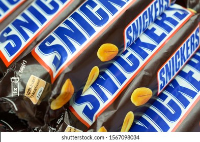 Many Snickers Chocolate Bars Stacked Close Up. Snickers Bars Are Produced By Mars Incorporated. Snickers Was Created By Franklin Clarence Mars In 1930