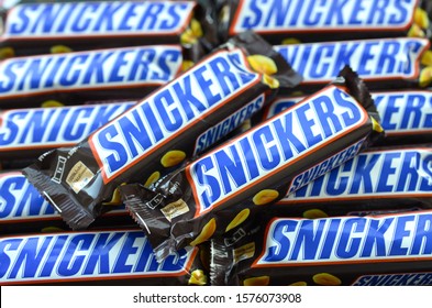 Many Snickers Chocolate Bars Stacked Close Up. Snickers Bars Are Produced By Mars Incorporated. Snickers Was Created By Franklin Clarence Mars In 1930