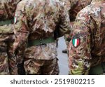 many soldiers of the Italian army with the Italian coat of arms with the green white and red flag and the camouflage uniform during the parade for the national holiday