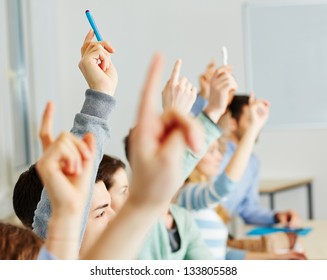Many students raising their hands in class for an answer