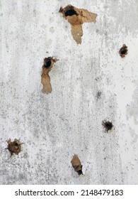 Many through holes from bullets in a wooden plywood painted wall throughout the frame