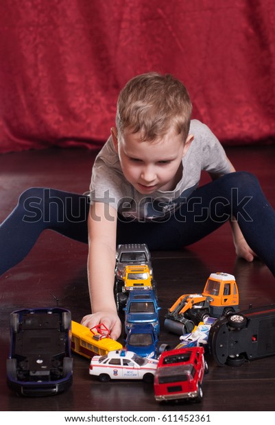 Many toy\
cars, little boy playing on the floor, the emergency situation on\
the road, the conceptual, dark hardwood\
floor