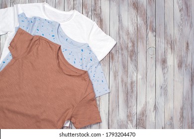 Many t-shirt on the wooden background. Fashion. Mockup with color blank t-shirts. Top view, flat lay. T-shirts folded. Different t-shirts preparing for printing. Copy space for your design.