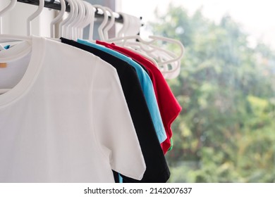 Many T-shirts Hanging On Towel Racks Or Clothesline Inside House.