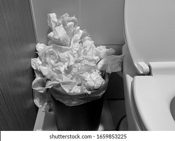 Many used toilet paper is thrown away in the garbage bin in the toilet, black and white photo