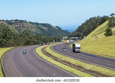 Many vehicles on N3 highway entering and leaving Pietermaritzburg against distant blue city skyline landscape in South Africa