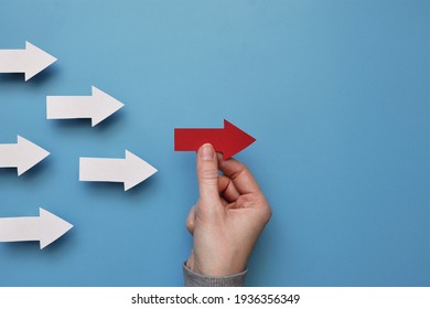 Many white arrows follow one red arrow. Symbol of following the leader straight to the goal - Shutterstock ID 1936356349