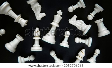 Many white chess pieces lie on the table against a black background.