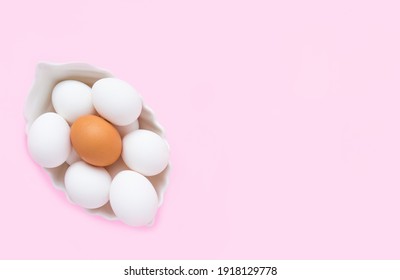 Many White Eggs And One Brown Egg In A White Dish On A Pink Background. Easter. Copy Space, Top View.