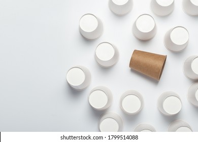 Many White And One Brown Paper Cups, Flipped Upside Down On A Light Background. Top View, Flat Lay.