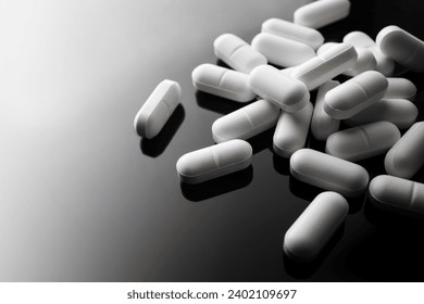 Many white pills on dark background. Selective focus.