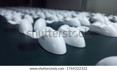 Many of the white plastic pieces that come out of the injection molding machine are arranged in rows,soft focus