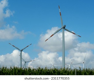 many windmills against a blue sky with clouds in the field.  summer - Shutterstock ID 2311770355