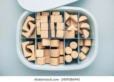 Many wooden geometric toys are kept in the same types of storage box, organization box with partitions, category concept