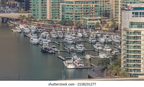 Many Yachts And Boats Are Parked In Harbor Aerial Timelapse. Dubai Marina Waterfront Walking Area. Modern Boat Is Riding The Creek. Traffic On A Bridge