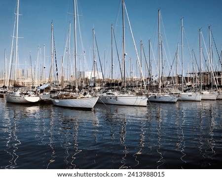 Many yachts moored in port, promenade of Barcelona, Spain at sunny day. Sailing and sea travel in Mediterranean Sea. Peaks of the match directed into sky, reflections on water. High quality photo