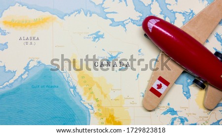 A map of Canada and a red plane with a flag of Canada attached to its wings.