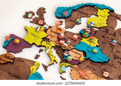 map of europe with flags, lots of round metal buttons with different flags of countries on the map of europe, wooden three-dimensional map of the world on a white background, politics, international