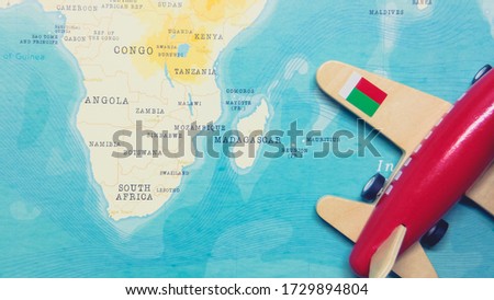 A map of Madagascar and a red plane with a flag of Madagascar attached to its wings.