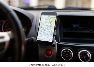 Die Karte auf dem Telefon im Hintergrund des Dashboard. Schwarzes Handy mit Karte GPS Navigation in der Montage. App-Karte für Reisen.
