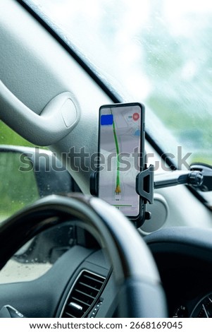 The map on the phone in the background of the dashboard and street. Black mobile phone with map GPS navigation fixed in the mounting. copy space. High quality vertical photo
