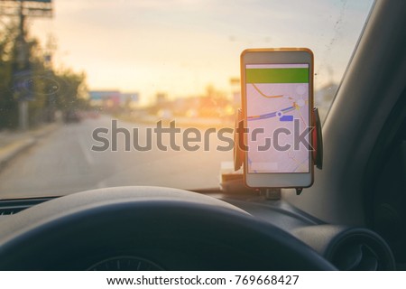 The map on the phone in the background of the dashboard and street . White mobile phone with map gps navigation fixed in the mounting. copy space.