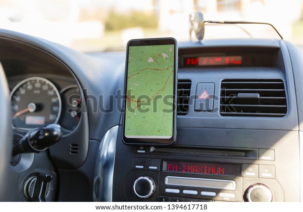 The map on the phone in the background of the\
dashboard. Black mobile phone with map gps navigation fixed in the\
mounting. App map for\
travel.