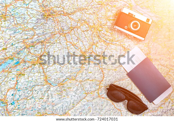 Map of roads with
a vintage camera, passport, sunglasses. View from above. The
concept of travel. Sun
flare