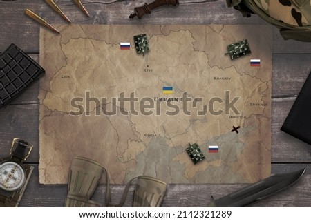 Map of the Russian invasion of Ukraine with military equipment on the table. Top view, flat lay concept composition