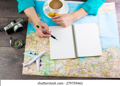 Map traveler. Woman bent over the map in search of a best route for the next vacation time to travel. Empty space in a notebook for blog entries, you can place your text. Top view - Powered by Shutterstock