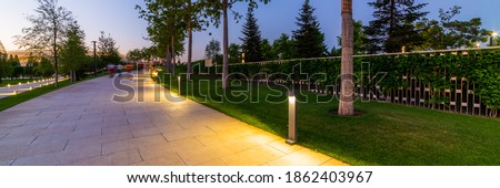 Maple alley in French garden in public landscape city park Krasnodar or Galitsky park . Wooden circular brown benches around maple trees