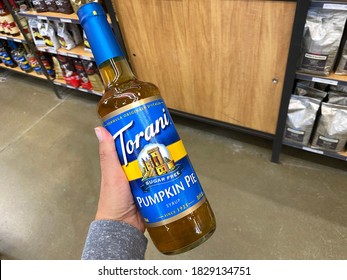 Maple Grove, Minnesota - October 5, 2020: Hand Holds Up A Glass Bottle Of Torani Pumpkin Pie Spice Sugar Free Flavored Syrup, Used For Coffee, Drinks And Baking