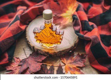 Maple syrup gift bottle in red maple tree leaves for tourist souvenir. Canada grade A amber sweet natural liquid from Quebec sugar shack maple trees farm.