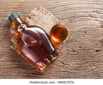 maple syrup in glass bottle on wooden table - Shutterstock ID 340417076