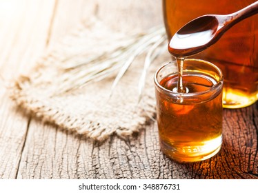 Maple Syrup In Glass Bottle On Wooden Table