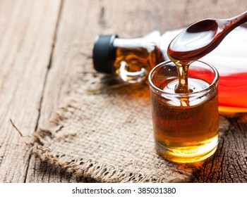 maple syrup in glass bottle on wooden table - Shutterstock ID 385031380