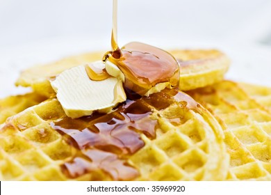 Maple Syrup Pouring Onto Waffles. Shallow DOF With Focus On Syrup And Butter.