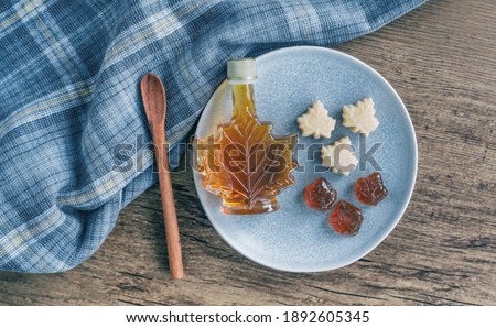 Maple syrup rustic table top view canadian natural product from Canada. Maple leaf shape gift bottle, soft candy and hard candy taffy candies kitchen cooking.