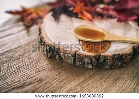 Maple syrup sugar liquid in wooden spoon from Quebec restaurant sugar shack called Cabane a sucre maple trees sap farm. Canadian delicacy sweet dessert ingredient,