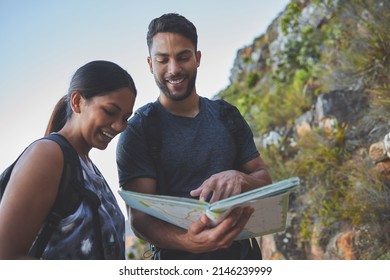 Maps Are So Helpful When Hiking. Shot Of A Young Couple Using A Guide Book To Complete A Hike In A Mountain Range.