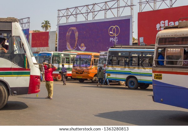Mapusa, Goa/India - 24.01.2019: A lot of\
Indian bright multi-colored buses parked at the bus station on the\
background of people and\
billboards