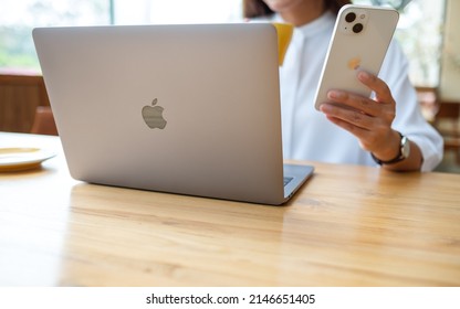 Mar 19th 2022 : A Woman Holding And Using Iphone 13 Smart Phone With Apple MacBook Pro Laptop Computer, Chiang Mai Thailand