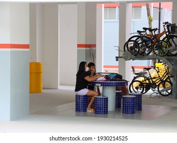 SINGAPORE–6 MAR 2021: A Void Deck Is An Open Space Found On The Ground Floor Of Housing Board Flats. It Is Used For Community Activities Or Meetings. A Foreign Domestic Worker With A Boy Wait There. 