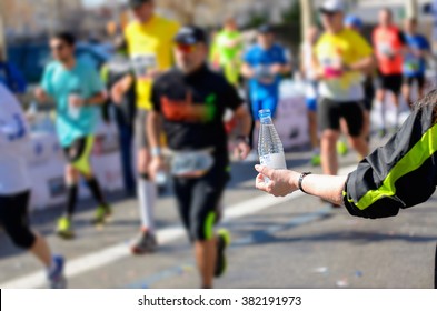 Marathon running race, runners on road, volunteer giving water on refreshment point
 - Powered by Shutterstock