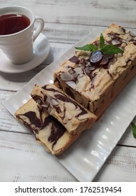 Marbel Cake Served On White Plate With A Cup Of Tea. White Wood Background