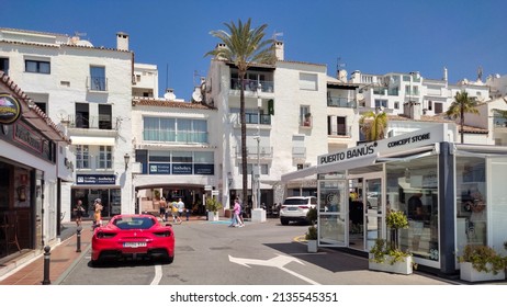 Marbella Malaga Spain June 12 2021. A red Ferrari parked on the street in the famous Puerto Banus area outside Marbella. People walking in the background. Small shops in the city center.